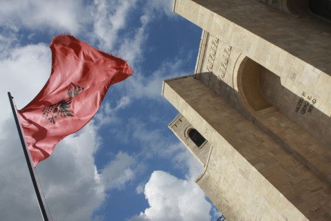 Albania, Kruja, National flag depicting black double headed eagle symbol on red background flying