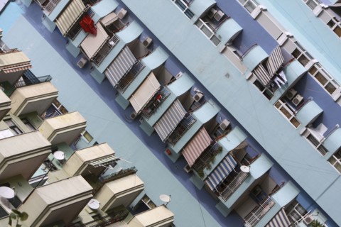 Albania, Tirane, Tirana, Angled view of balconies  striped awnings and satellite dishes on blue