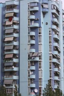 Albania, Tirane, Tirana, Balconies and striped awnings on blue painted exterior facade of multi
