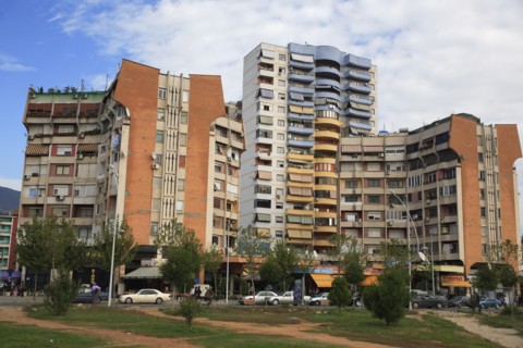 Albania, Tirane, Tirana, Apartment blocks with shops below  overlooking road and area of grass and