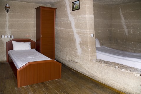 Room with bed in typical cave hotel carved from volcanic tufa rock. Photo : Hugh Rooney