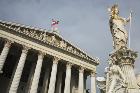 Statue of Athena raised on pillar above fountain in front of the Parliament building colonnaded