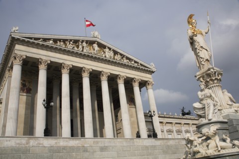 Statue of Athena raised on pillar above fountain in front of the Parliament building colonnaded