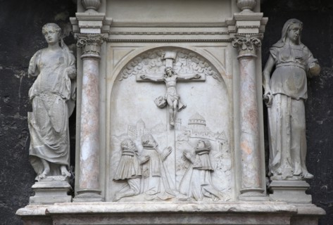 Stone relief carving of the crucifixion flanked by statues on the outside of the Stephansdom
