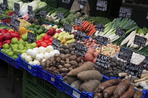 Vegetable stall in the Naschmarkt with display of produce including yams shallots and leeks. Photo: