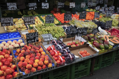 Fruit stall in the Naschmarkt with display of produce including peaches plums grapes and mangoes.