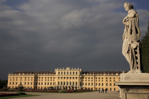 Schonnbrunn Palace. Exterior with statue of standing figure in foreground beneath grey stormy sky.