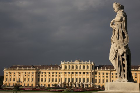 Schonnbrunn Palace. Exterior with statue of standing figure in foreground beneath grey stormy sky.