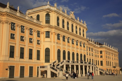 Schonnbrunn Palace. Angled part view of exterior facade with tourist visitors in courtyard and on