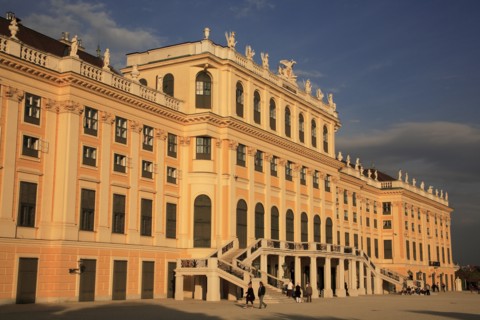 Schonnbrunn Palace. Part view of exterior facade with tourist visitors in courtyard in foreground.