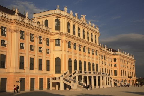 Schonnbrunn Palace. Part view of exterior facade with tourist visitors in courtyard in foreground.