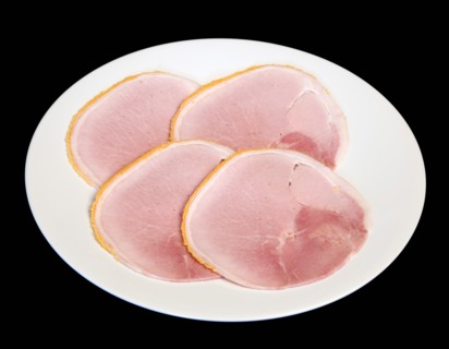 Slices of cured ham on a round white plate on a black background. Photo: Paul Seheult