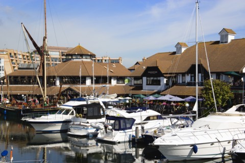 Port Solent Boats moored in the marina with people sitting at restaurant tables beyond beside a pub