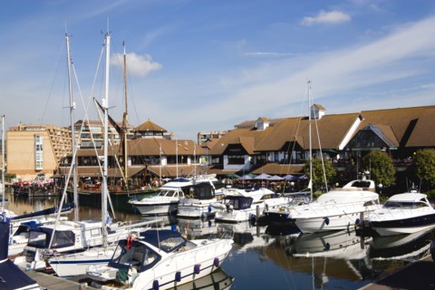 Port Solent Boats moored in the marina with people sitting at restaurant tables beyond beside a pub