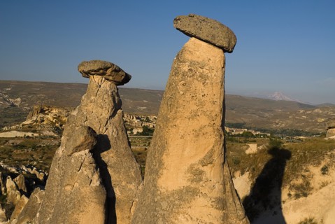 Urgup. Fairy chimney rock formations with Mount Erciyes in the background in warm golden light.