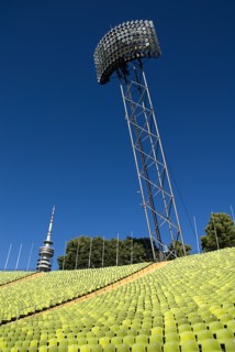 Olympic Stadium. Angled view across green seating of the stadium with floodlight and part view of