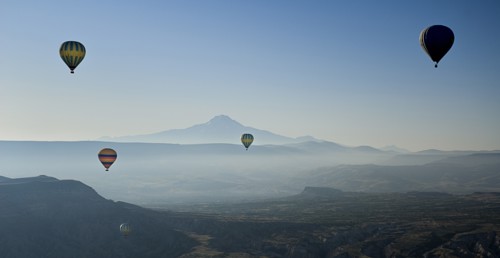 Early morning with hot air balloons in flight mist drifting across landscape and Mount Erciyes in