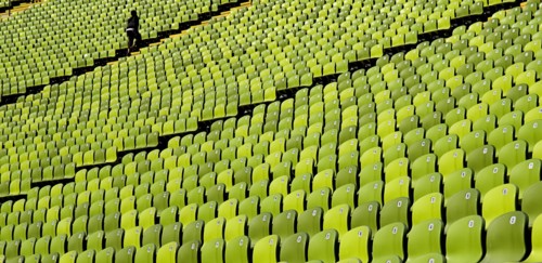 Olympic Stadium. Curved section of bright green seating in the stadium with standing figure at far