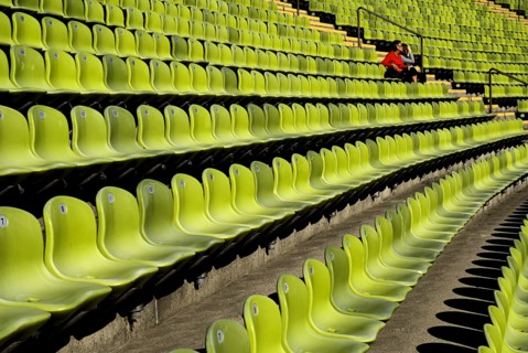 Olympic Stadium. Curved section of bright green seating in the stadium with couple seated at far