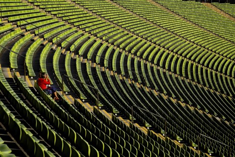 Olympic Stadium. Curved section of bright green seating in the stadium with seated figure centre