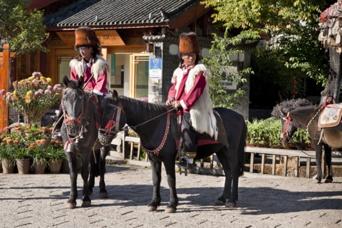Naxi men on horseback wearing traditional costume including Red panda skin hats. Photo : Mel