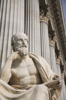Statue of the Greek philosopher Herodotus in front of columns of the Parliament Building. Photo :