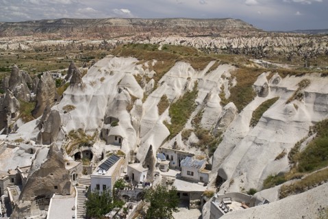 Looking down on a cave hotel built into the white tufa rock with the Red Valley behind. Photo :