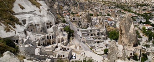 Cave hotel built into white tufa rock of hillside with part view of the town beyond. Photo: Hugh
