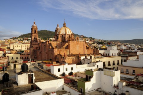 Mexico, Bajio, Zacatecas, View across flat rooftops of houses towards Cathedral. 
Photo : Nick