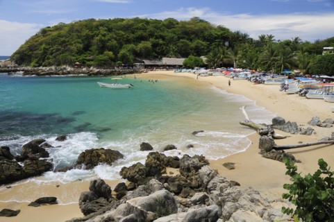 Mexico, Oaxaca, Puerto Escondido, View onto Playa Manzanillo beach with rocks and driftwood in