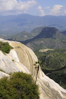 Mexico, Oaxaca, Hierve el Agua, Tourist standing on limestone cliff looking out over surrounding