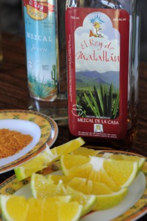 Mexico, Oaxaca, Bottles of Mezcal and plate of orange slices. 
Photo : Nick Bonetti