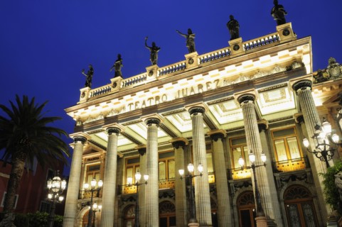 Mexico, Bajio, Guanajuato, lluminated exterior facade of Theatre Juarez with line of rooftop