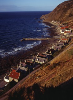 Scotland, Aberdeenshire, Crovie, One time fishing village seen from cliff top. Row of cottages at