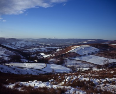 England, Derbyshire, Hathersage, View westwards over snow covered moorland landscape and fields