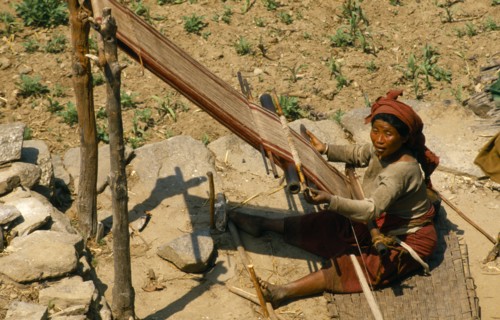 Nepal, East, Gudel, Woman sitting on ground to weave textile on hand loom. 
Photo : Chris Beall