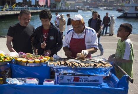Turkey, Istanbul, Karakoy Galata fish market man selling freshly grilled fish served in bread roll.