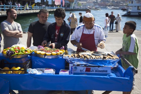 Turkey, Istanbul, Karakoy Galata fish market man selling freshly grilled fish served in bread roll.