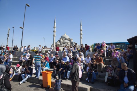 Turkey, Istanbul, Eminonu Yeni Camii New Mosque people on sat on steps next to the subway. 
Photo