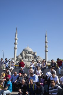 Turkey, Istanbul, Eminonu Yeni Camii New Mosque people on sat on steps next to the subway. 
Photo