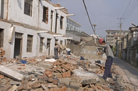 China, Jiangsu, Qidong, Demolition workers using hammers with flexible handles to demolish old