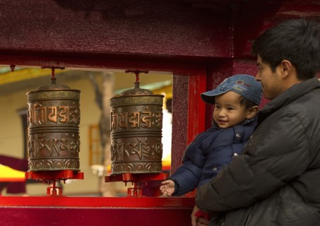 Father and son devotees turning prayer wheels at a Buddhist  Monastery, Sikkim, India