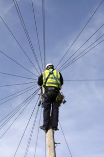 Communications, Telephones, Telecommunications engineer working on phone lines at the top of a