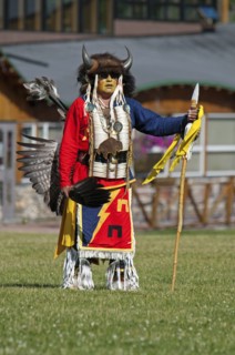 Blackfoot dancer in a buffalo headdress and sunglasses wearing a porcupine quill breastplate and holding a spear and feather fan at the Blackfoot Arts & Heritage Festival Pow Wow organized by Parks Ca...