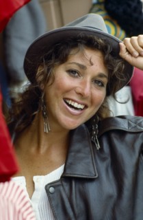 Smiling teen girl wearing hat and leather jacket.