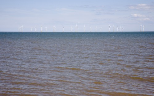 Wind Farm offshore on the horizon showing turbine blades.