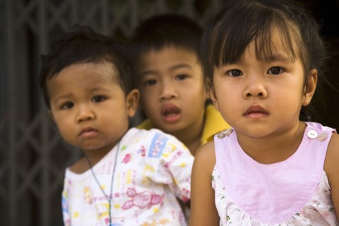 Young children in late afternoon sun in front of shophouse entrance.