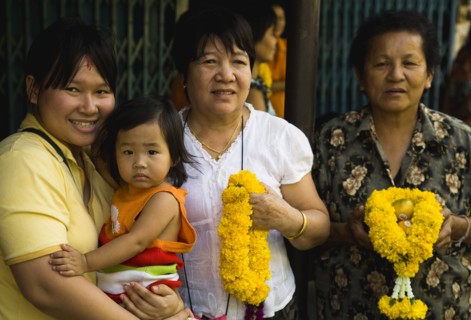 Four female generations of family with floral garlands to celebrate the annual blessing of local temple.