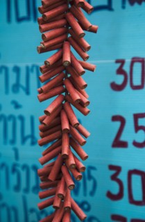 Firecrackers celebrating local temple in front of Thai script on menu board