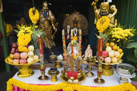 Offerings on table with Guanyin Goddess of Mercy statue in centre celebrating local temple.